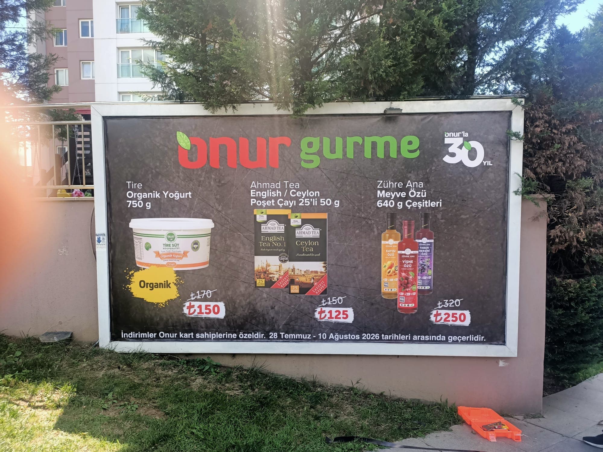 Yoğurt, çay ve meyve özü görselleri ile fiyat etiketleri taşıyan market kampanyası panosu