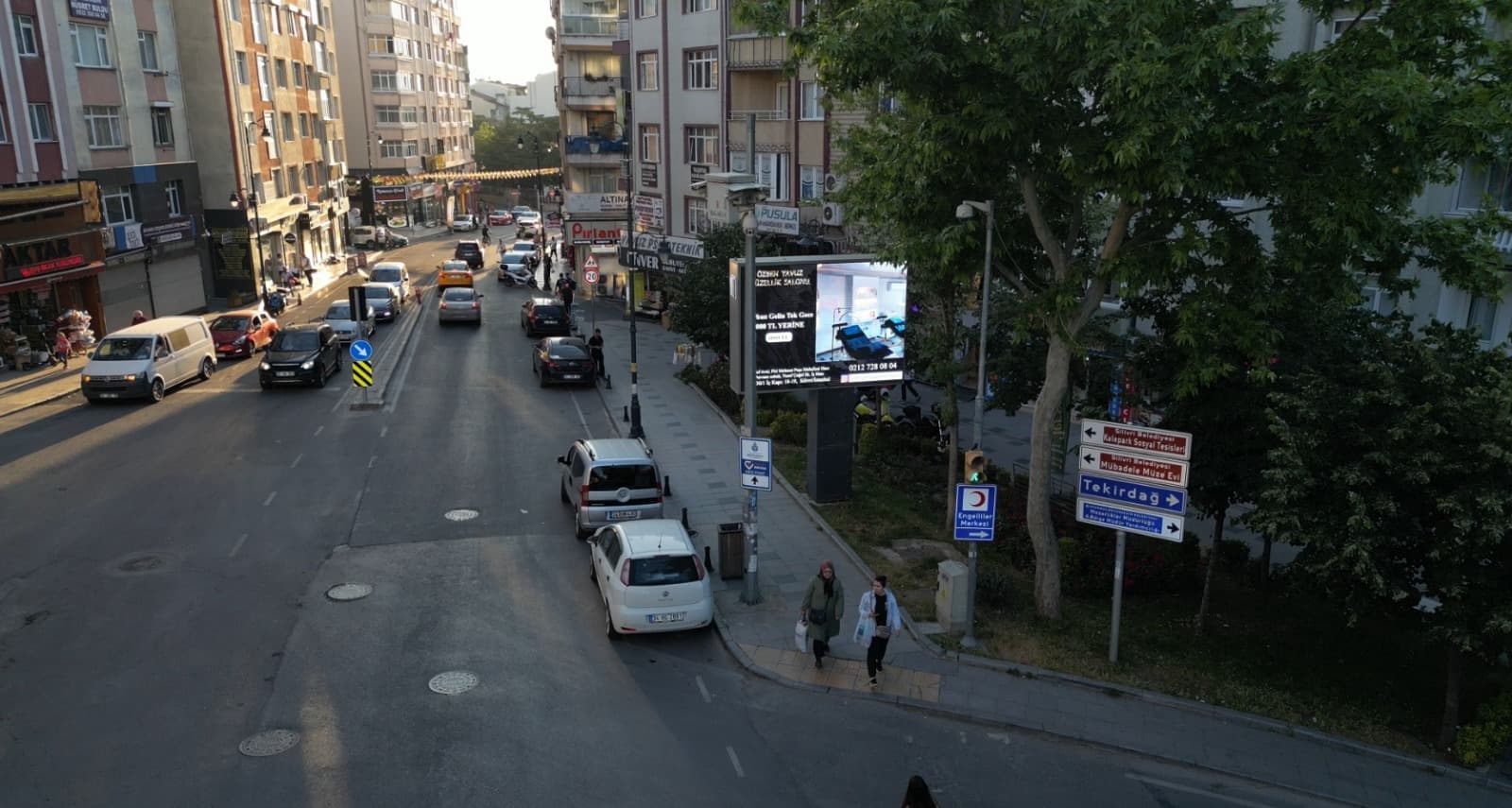 Kavşak kenarında reklam yayınlayan LED ekranın ve akan trafiğin havadan görünümü