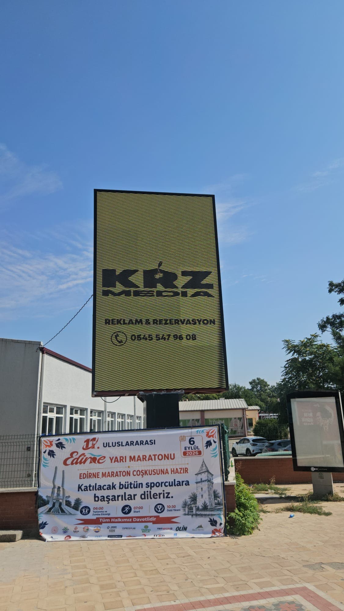 Mavi gökyüzü önünde KRZ Medya tanıtımı yayınlayan dikey LED totemin yakından görünümü